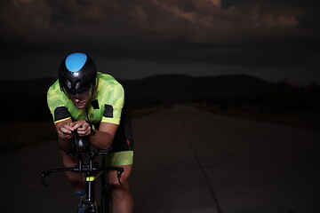 Image showing triathlon athlete riding bike fast at night