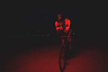 Image showing triathlon athlete riding bike fast at night