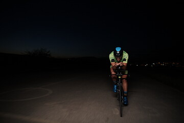 Image showing triathlon athlete riding bike fast at night