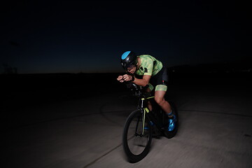 Image showing triathlon athlete riding bike fast at night