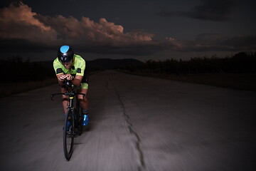 Image showing triathlon athlete riding bike fast at night