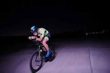 Image showing triathlon athlete riding bike fast at night