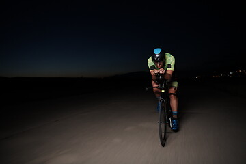 Image showing triathlon athlete riding bike fast at night