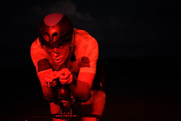 Image showing triathlon athlete riding bike fast at night