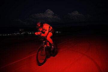 Image showing triathlon athlete riding bike fast at night