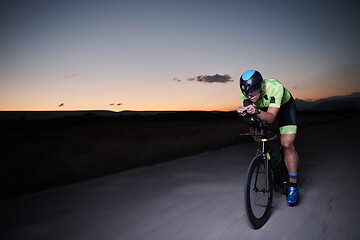 Image showing triathlon athlete riding bike fast at night