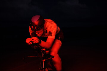 Image showing triathlon athlete riding bike fast at night