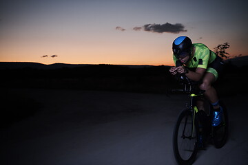 Image showing triathlon athlete riding bike fast at night