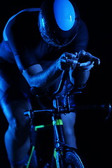 Image showing triathlon athlete riding bike fast at night