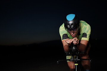 Image showing triathlon athlete riding bike fast at night