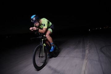 Image showing triathlon athlete riding bike fast at night