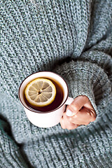 Image showing Female hands holding mug of hot tea with lemon in morning.