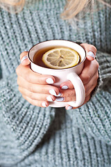 Image showing Female hands holding mug of hot tea with lemon in morning.