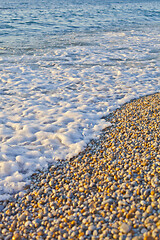 Image showing Pebble stones by the sea. Waves of blue Tyrrhenian sea.