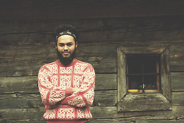 Image showing portrait of young hipster in front of wooden house