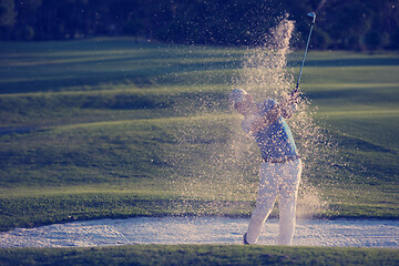 Image showing golfer hitting a sand bunker shot on sunset