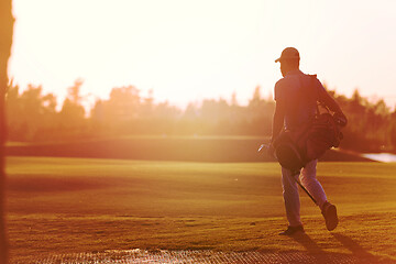 Image showing golfer  walking and carrying golf  bag at beautiful sunset