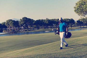 Image showing golf player walking and carrying bag