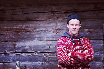 Image showing young hipster in front of wooden house