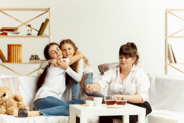 Image showing Little girls, attractive young mother and charming grandmother are sitting at home