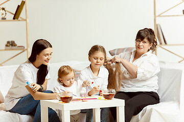 Image showing Little girls, attractive young mother and charming grandmother are sitting at home