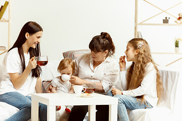 Image showing Little girls, attractive young mother and charming grandmother are sitting at home