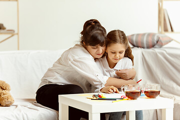Image showing Little girl and charming grandmother are sitting at home
