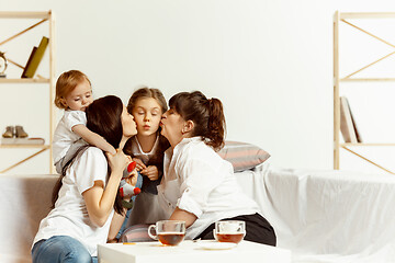 Image showing Little girls, attractive young mother and charming grandmother are sitting at home