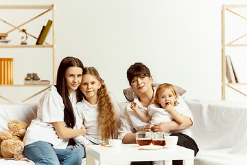 Image showing Little girls, attractive young mother and charming grandmother are sitting at home