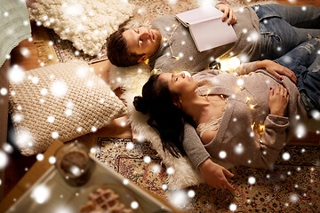 Image showing happy couple with garland lying on floor at home