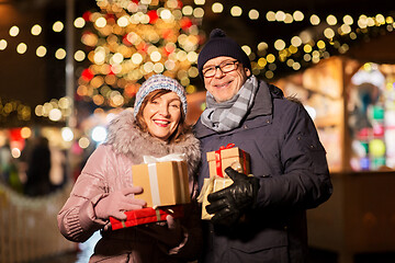 Image showing happy senior couple with gift at christmas market