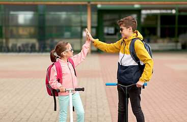 Image showing happy school children with backpacks and scooters