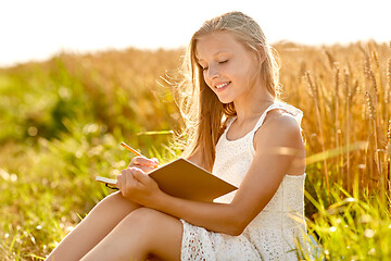 Image showing smiling girl writing to diary on cereal field