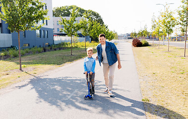 Image showing happy father and little son riding scooter in city