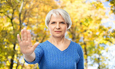 Image showing senior woman making stop gesture in autumn park