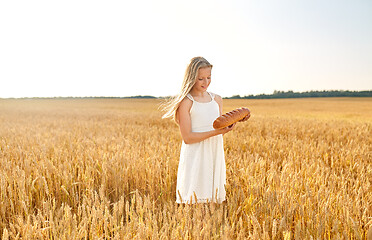 Image showing girl with loaf of white bread on cereal field