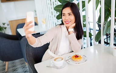 Image showing asian woman taking selfie by smartphone at cafe