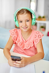 Image showing girl in headphones listening to music on cellphone