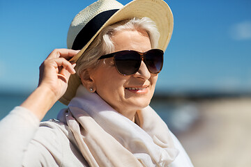 Image showing happy senior woman in sunglasses and hat on beach