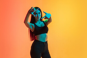 Image showing Young woman\'s portrait on yellow-orange studio background in neon light