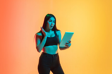 Image showing Young woman\'s portrait on yellow-orange studio background in neon light