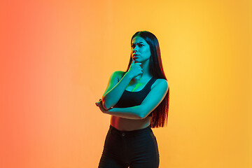 Image showing Young woman\'s portrait on yellow-orange studio background in neon light