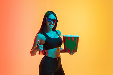 Image showing Young woman\'s portrait on yellow-orange studio background in neon light