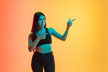 Image showing Young woman\'s portrait on yellow-orange studio background in neon light