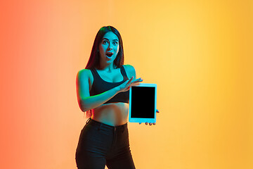 Image showing Young woman\'s portrait on yellow-orange studio background in neon light