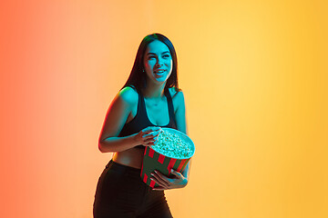 Image showing Young woman\'s portrait on yellow-orange studio background in neon light