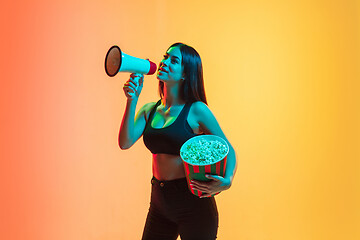 Image showing Young woman\'s portrait on yellow-orange studio background in neon light