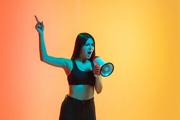 Image showing Young woman\'s portrait on yellow-orange studio background in neon light