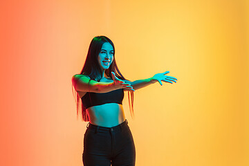 Image showing Young woman\'s portrait on yellow-orange studio background in neon light