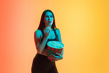 Image showing Young woman\'s portrait on yellow-orange studio background in neon light